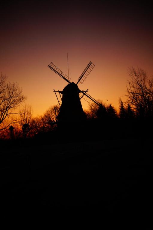 een silhouet van een windmolen bij zonsondergang bij FeWo Düver in Loxstedt