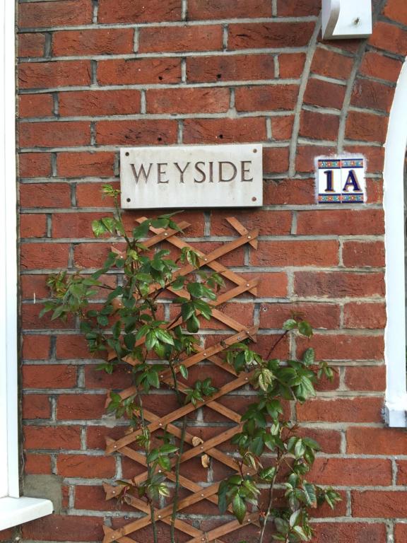 una señal en el costado de una pared de ladrillo en Weyside House en Weymouth