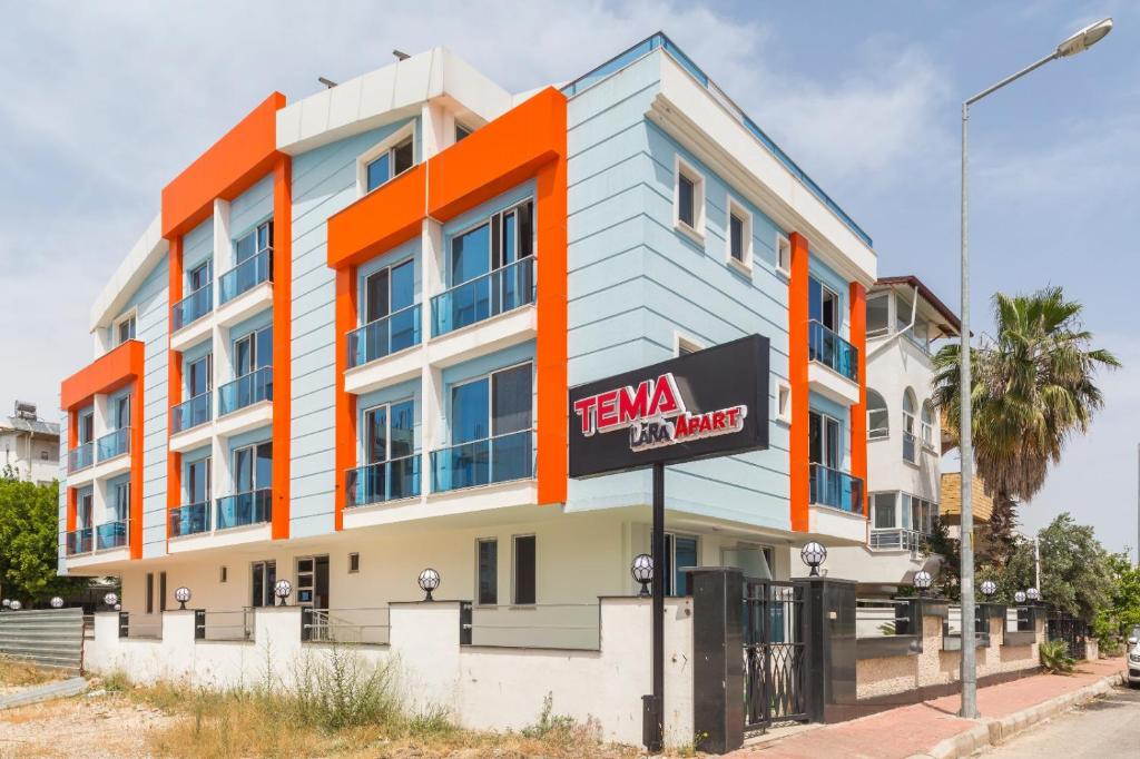 un bâtiment orange et blanc avec un panneau devant lui dans l'établissement TEMA LARA APART, à Antalya