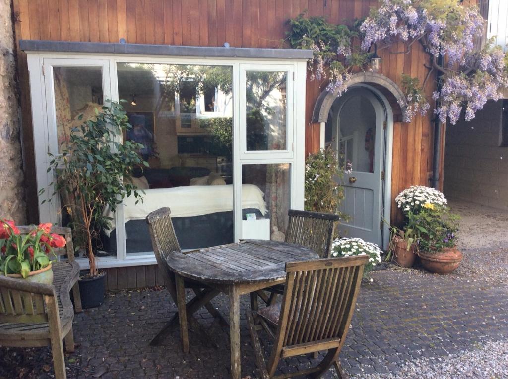 a patio with a table and chairs and a bed in a window at Arch Cottage in Chagford