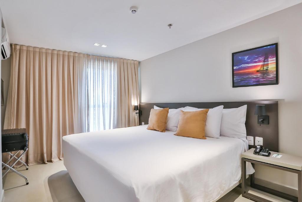 a large white bed in a hotel room at Quality Suítes João Pessoa in João Pessoa
