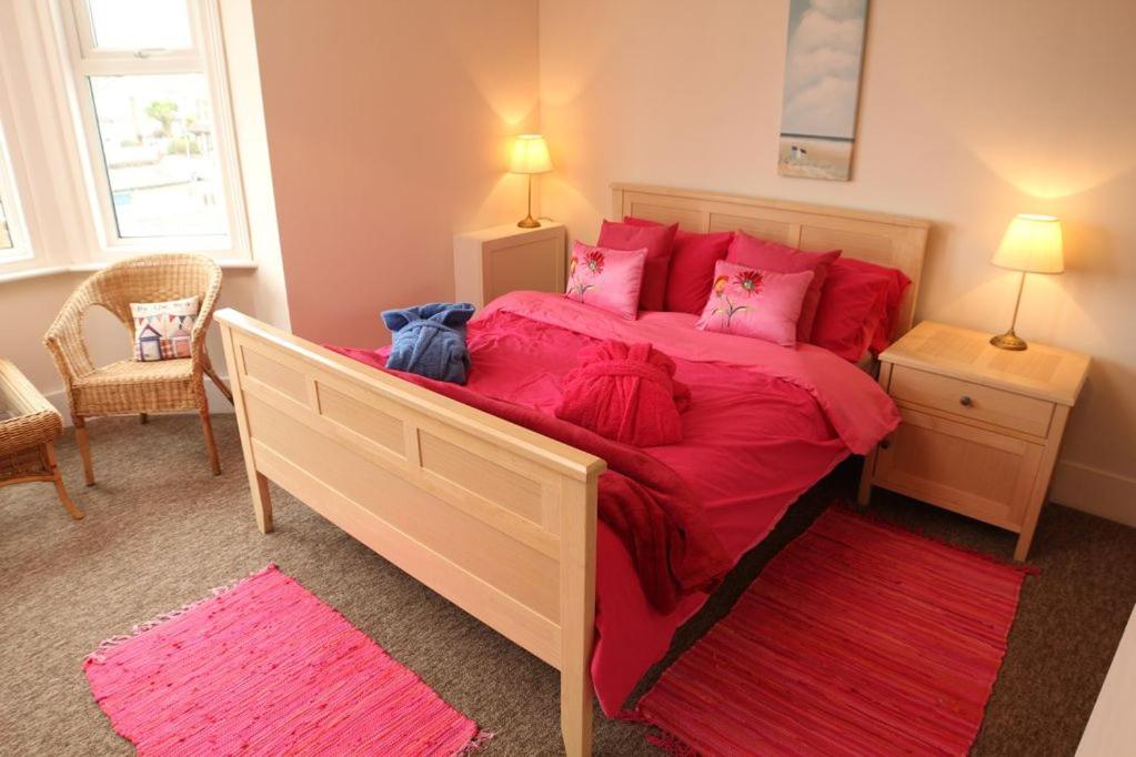 1 dormitorio con 1 cama grande con sábanas y almohadas rojas en Evee's Pebbles 1, en Eastbourne