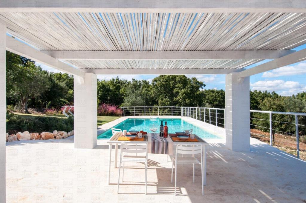un patio con tavolo e sedie accanto alla piscina di Golden Hill Trulli with Pool - large garden for furry friends a Ceglie Messapica