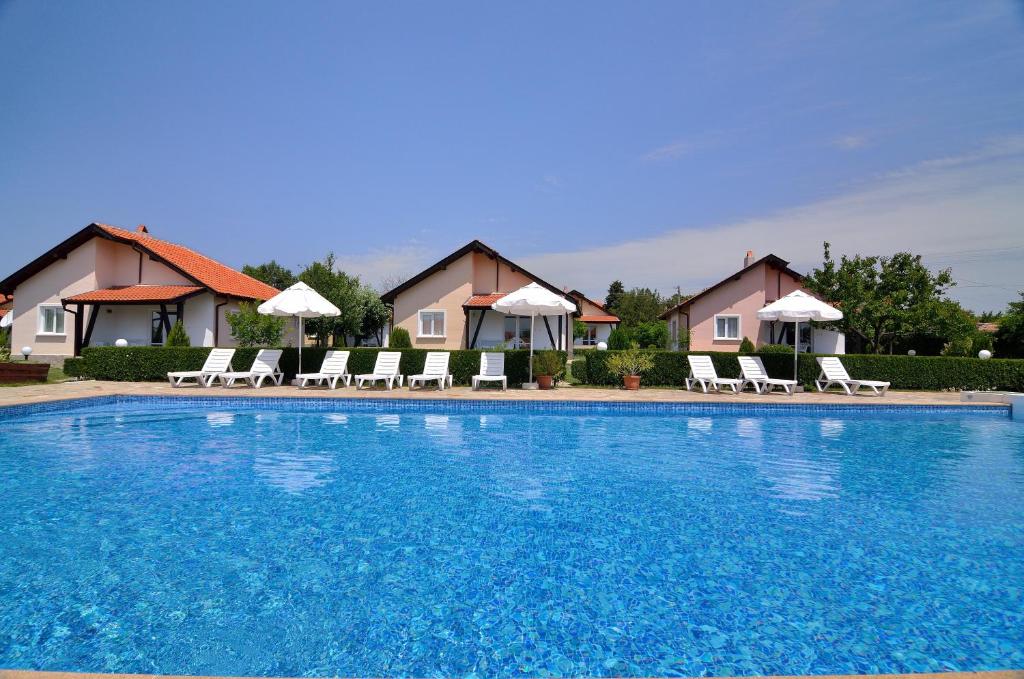 a large blue swimming pool with chairs and umbrellas at Sunny Hills Villas in Bryastovets
