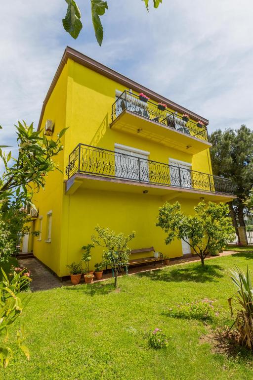 żółty dom z balkonem i dziedzińcem w obiekcie Apartment Mery w Puli