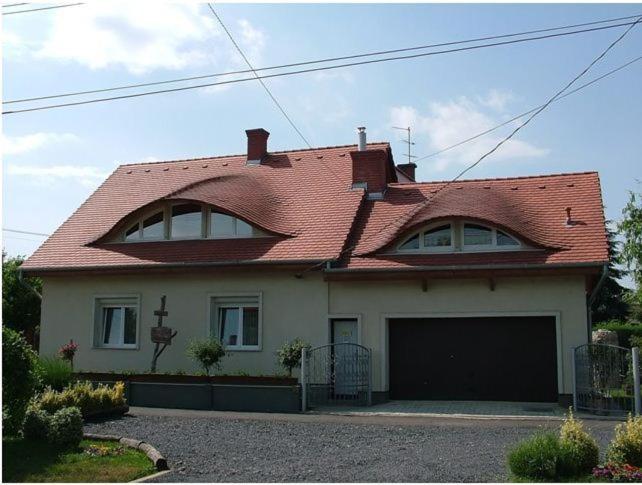 una casa con techo rojo y garaje en Luca Vendégház, en Sárvár