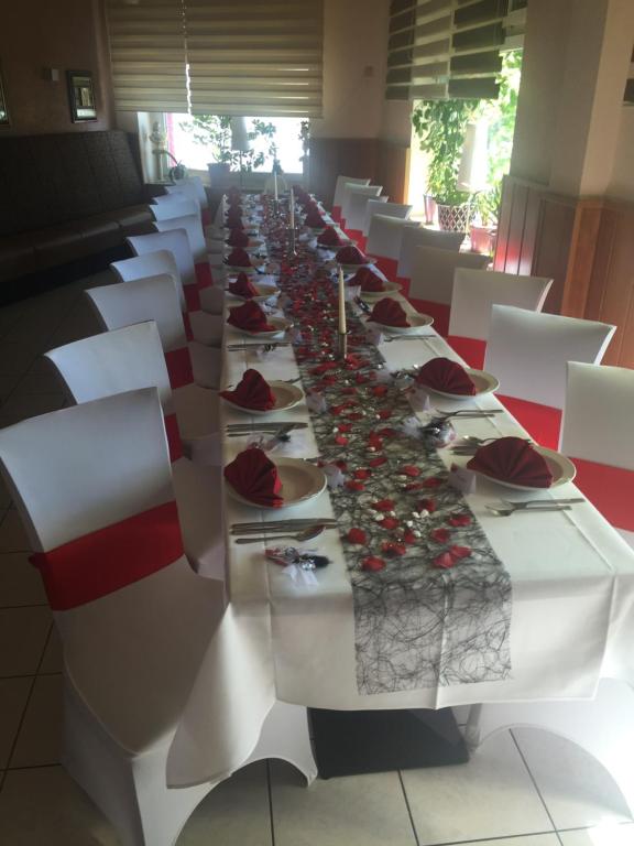 une grande table avec des tables blanches et des chaises blanches dans l'établissement Hotel Restaurant Alexandros, à Mannheim