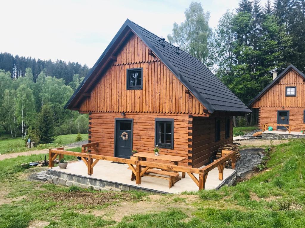 a log cabin with a large deck in a field at Roubenky Bublava in Bublava