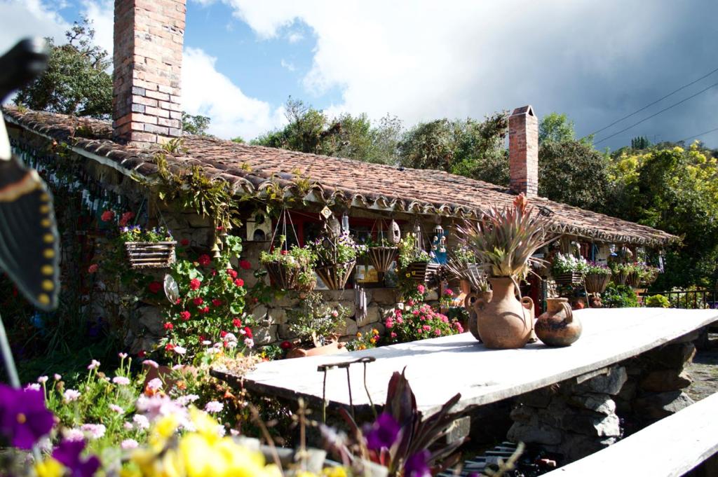 a house with flowers and plants in front of it at Casa de piedra El Colibrí in Guasca