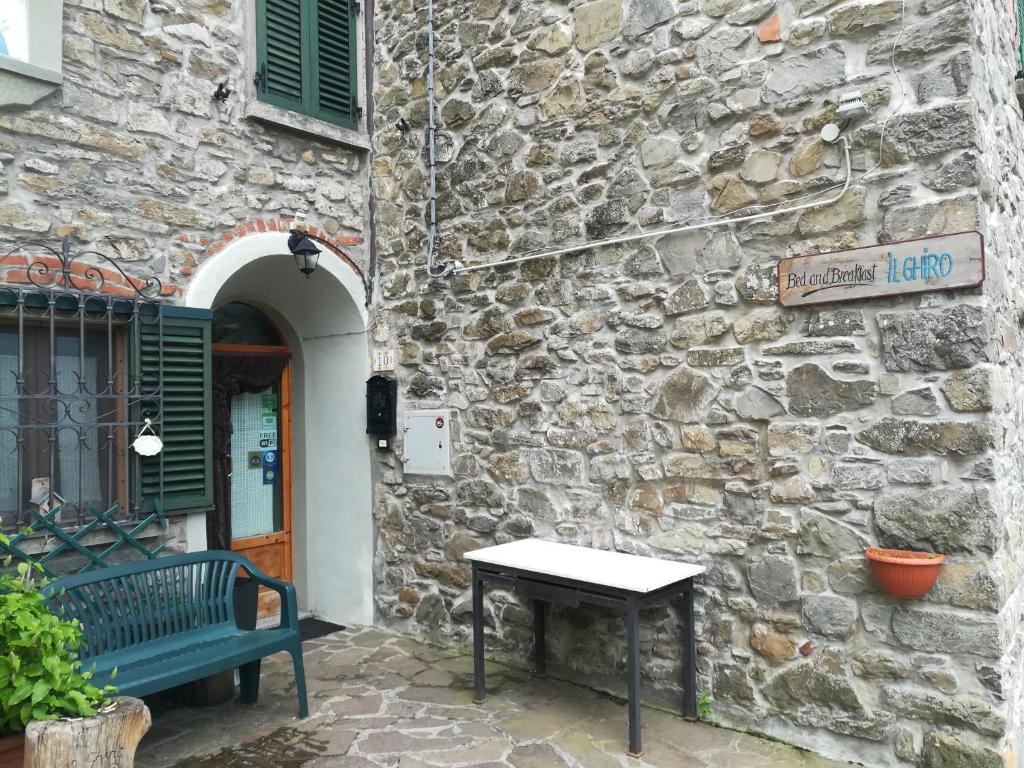 a bench in front of a stone building with a door at B&B Il Ghiro in Pracchia