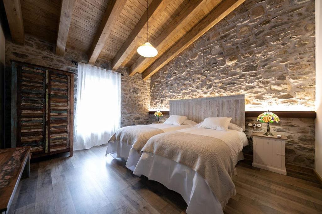 a bedroom with a bed and a stone wall at Sports House Nord Sud (Only Adults) in Vilallonga de Ter