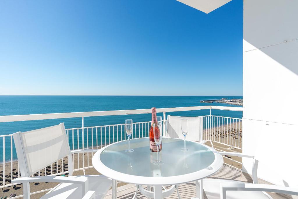 einen weißen Tisch und Stühle auf einem Balkon mit Meerblick in der Unterkunft MalagaSuite Malagueta Impressive Views in Málaga