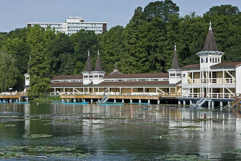 a large building on the water next to a river at Ensana Thermal Hévíz in Hévíz