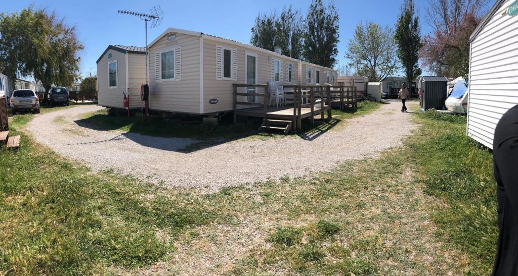 un mobile home est garé à côté d'une maison dans l'établissement Camping Horizon Bar, à Frontignan