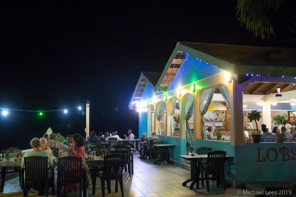 a restaurant with people sitting at tables at night at Sunset Bay Club All Inclusive in Colihaut
