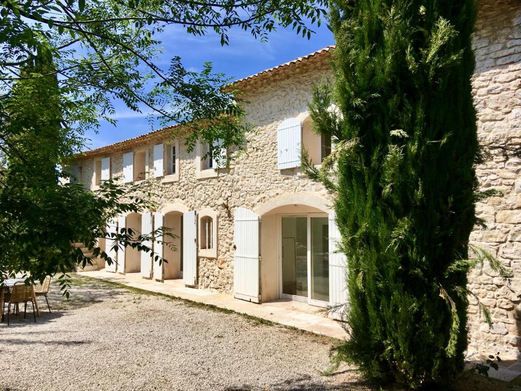 a stone house with a courtyard and trees at Domaine de Carraire in Aix-en-Provence