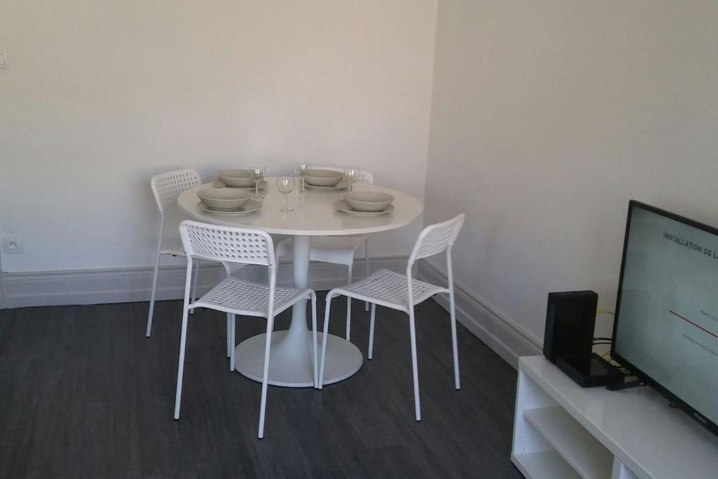 Biały stół jadalny z białymi krzesłami i telewizor w obiekcie F3 lumineux & cosy au centre de Mulhouse w Miluzie