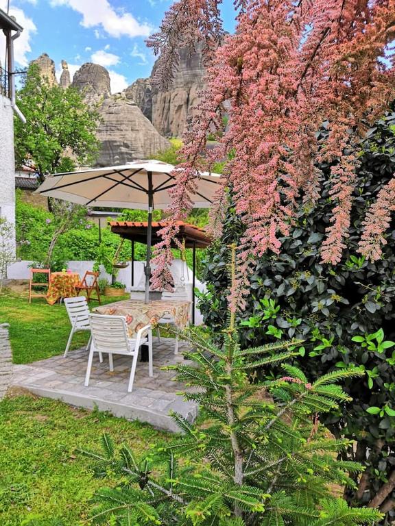 a table and chairs under an umbrella in a garden at Sotiris Idyllic Garden House in Kalabaka