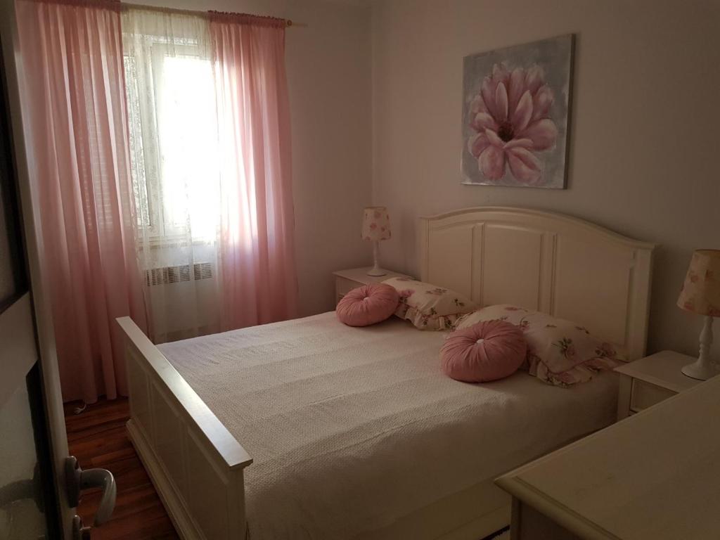 Schlafzimmer mit einem Bett mit rosa Kissen und einem Fenster in der Unterkunft Cozy apartment in Rovinj in Rovinj
