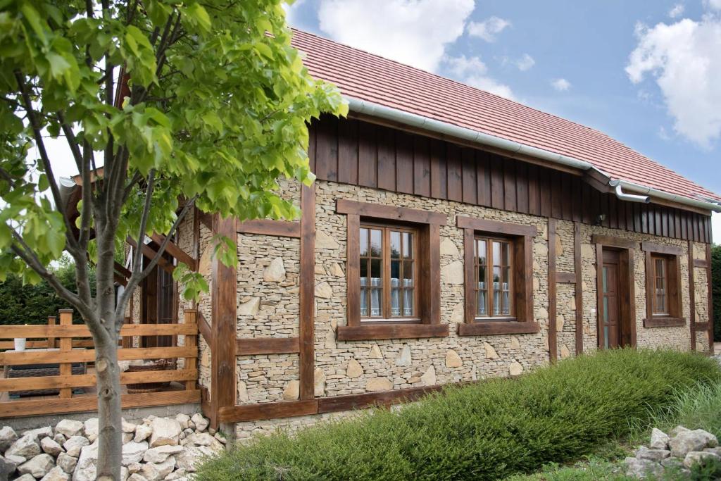 Cabaña de piedra con ventanas y árbol en Pine Cottage, en Cserszegtomaj