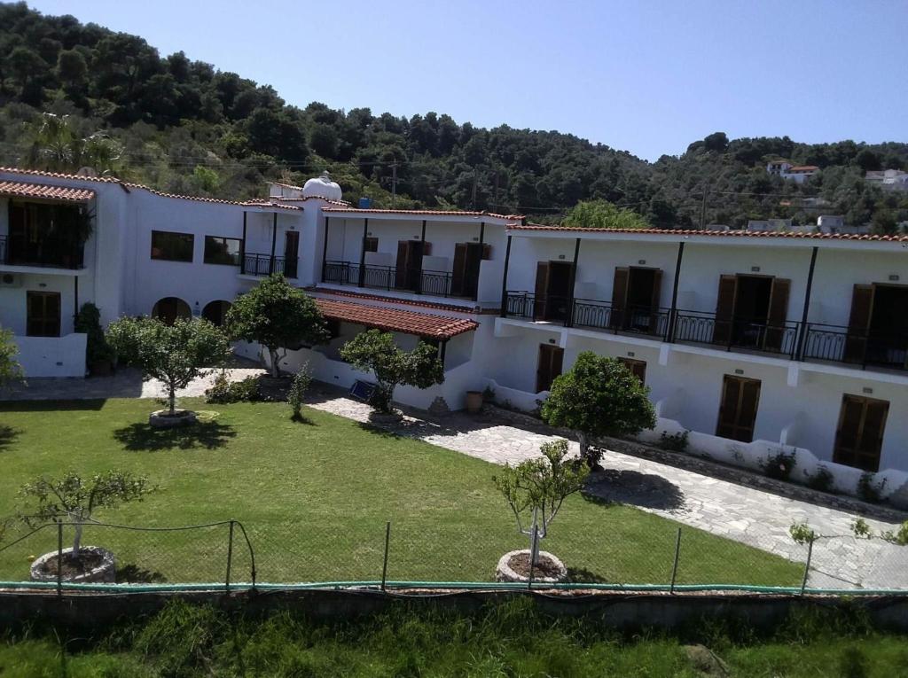 a large white building with a yard with trees at Vontzos Hotel in Achladies
