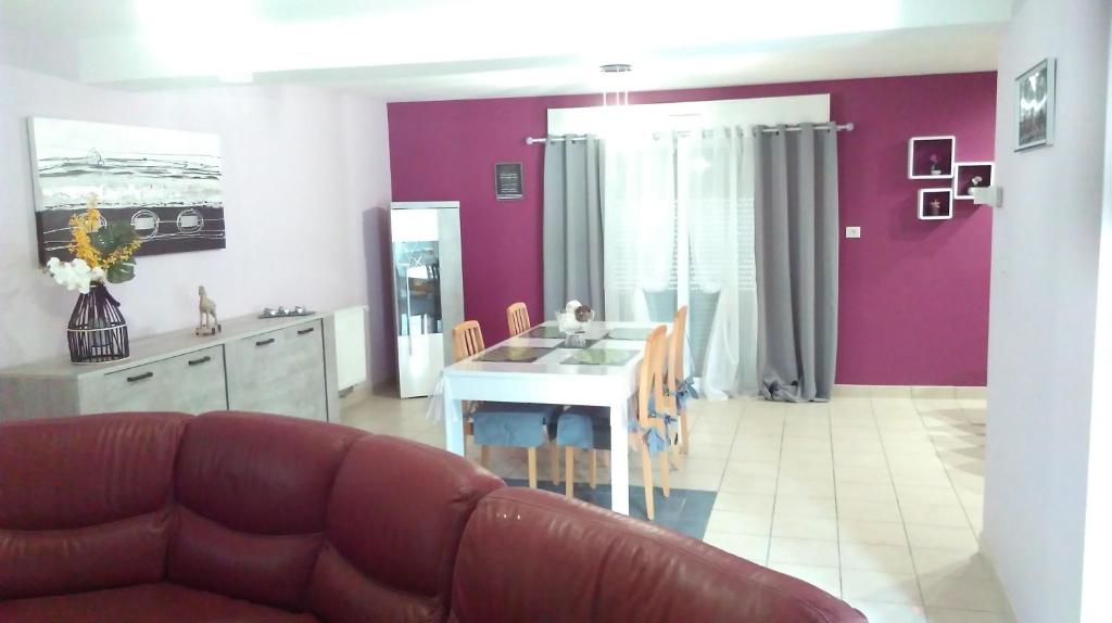 sala de estar con sofá y cocina con paredes moradas. en la maison du bonheur, en Roquetoire
