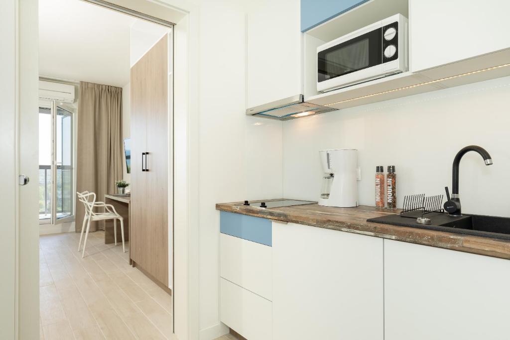eine Küche mit einer Spüle und einer Mikrowelle über einer Theke in der Unterkunft Aquamarina Onyx Marina Invest in Misdroy
