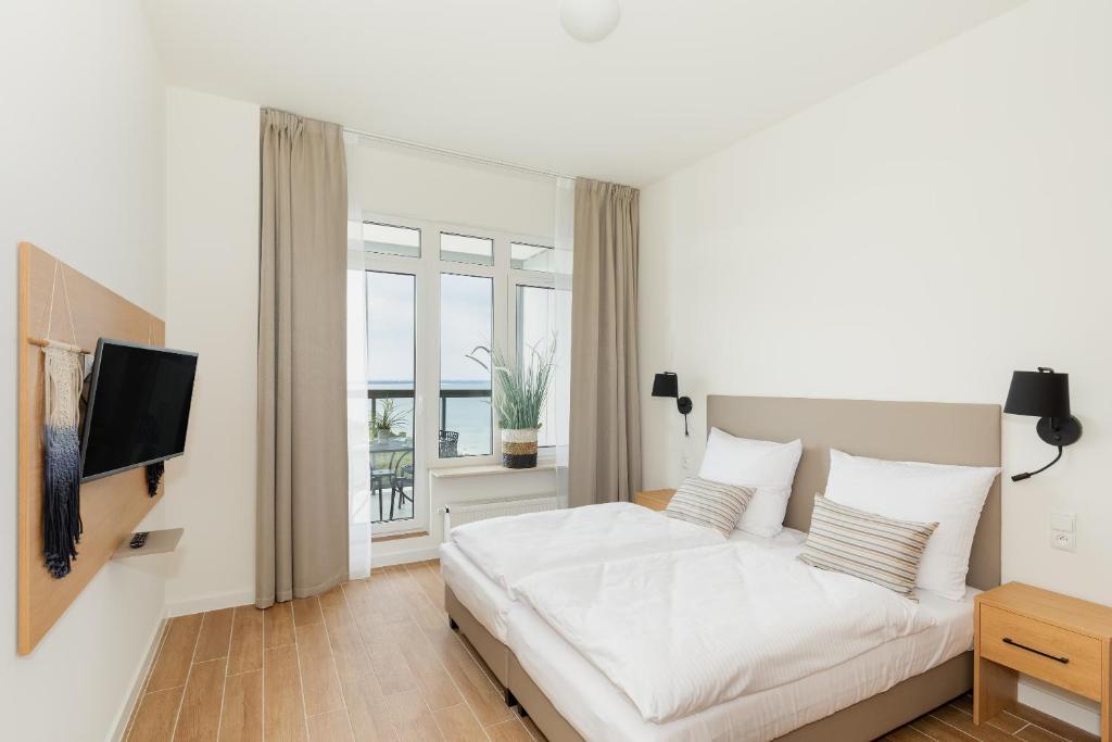 ein weißes Schlafzimmer mit einem Bett und einem Fernseher in der Unterkunft Aquamarina Onyx Marina Invest in Misdroy