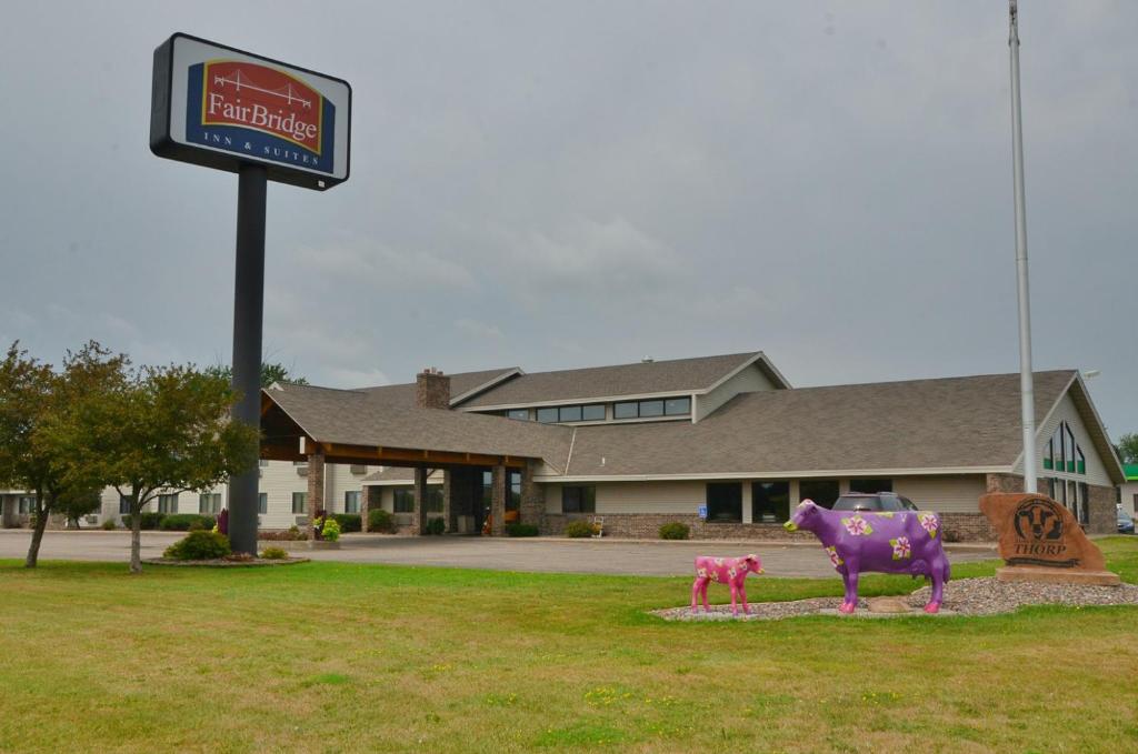 una statua di una mucca viola di fronte a un edificio di FairBridge Inn & Suites a Thorp