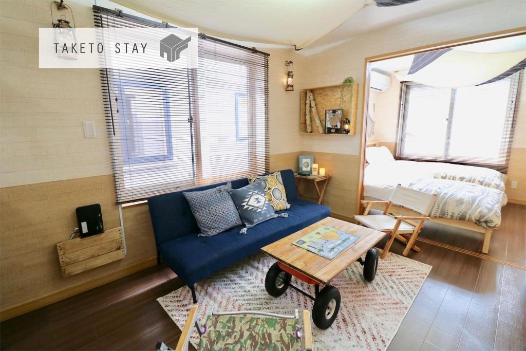 uma sala de estar com um sofá azul e uma cama em Jeunesse Court em Sapporo