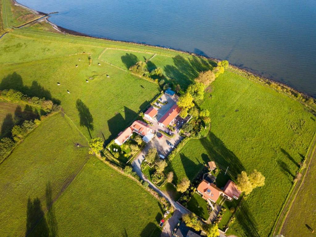 an aerial view of a house in a field next to the water at Ostseehotel Hunhoi in Niesgrau