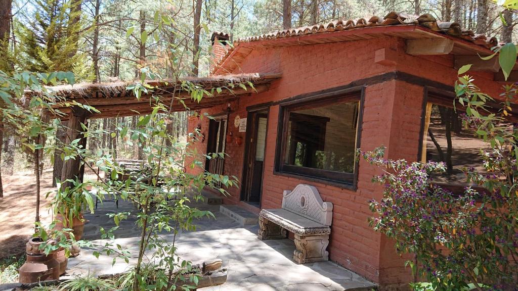 a small brick house with a bench in a yard at Cabañas tapalpa Sierra del Tecuan, Cabaña Tejón in Tapalpa