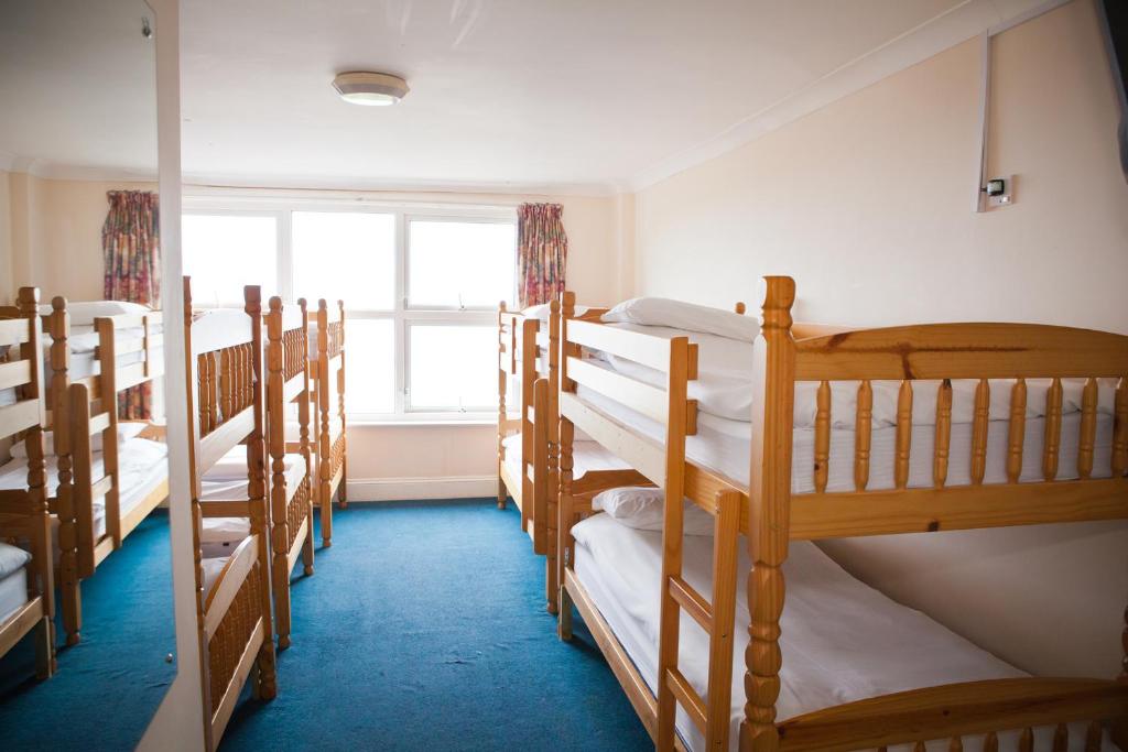 eine Reihe von Etagenbetten in einem Zimmer mit Fenster in der Unterkunft Berties Lodge in Newquay