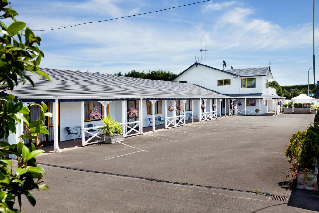 a large white building with a large parking lot at Accommodation at Te Puna Motel in Tauranga