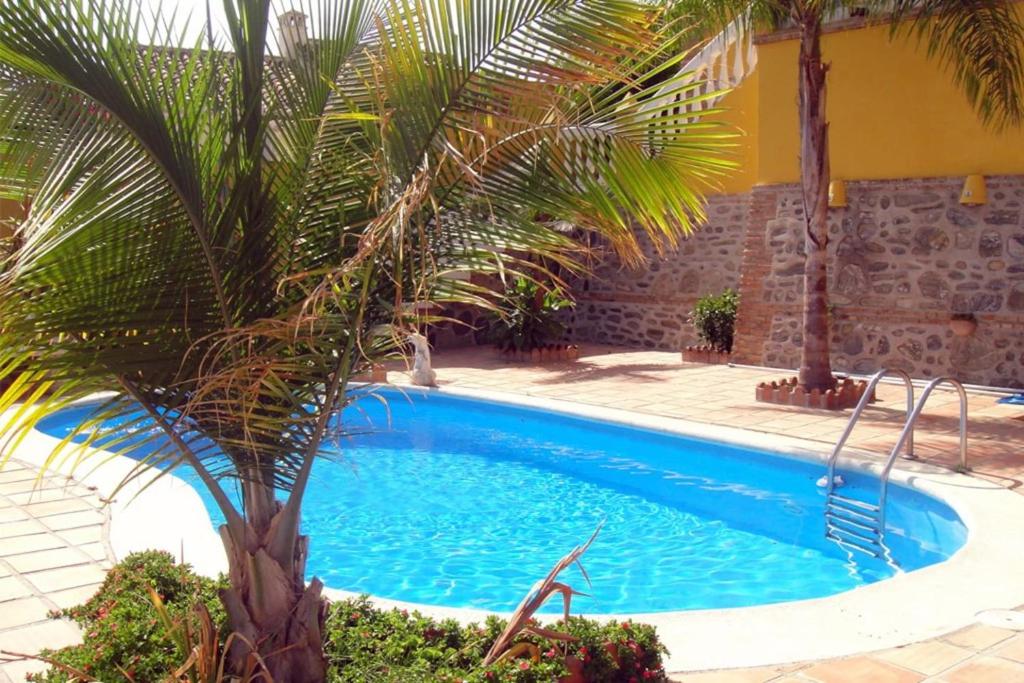 una piscina con una palma accanto a un edificio di CHALET CON PISCINAS Y VISTAS DE ENSUEÑO ad Almuñécar
