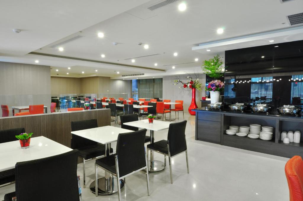 a restaurant with white tables and chairs and a kitchen at Goodness Plaza Hotel in Taishan