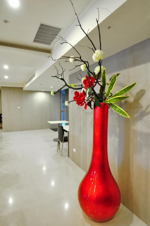 a red vase with red flowers in a room at Goodness Plaza Hotel in Taishan