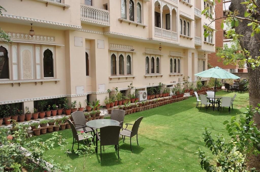 un patio de un edificio con sillas, mesas y sombrilla en Om Niwas Suite Hotel, en Jaipur
