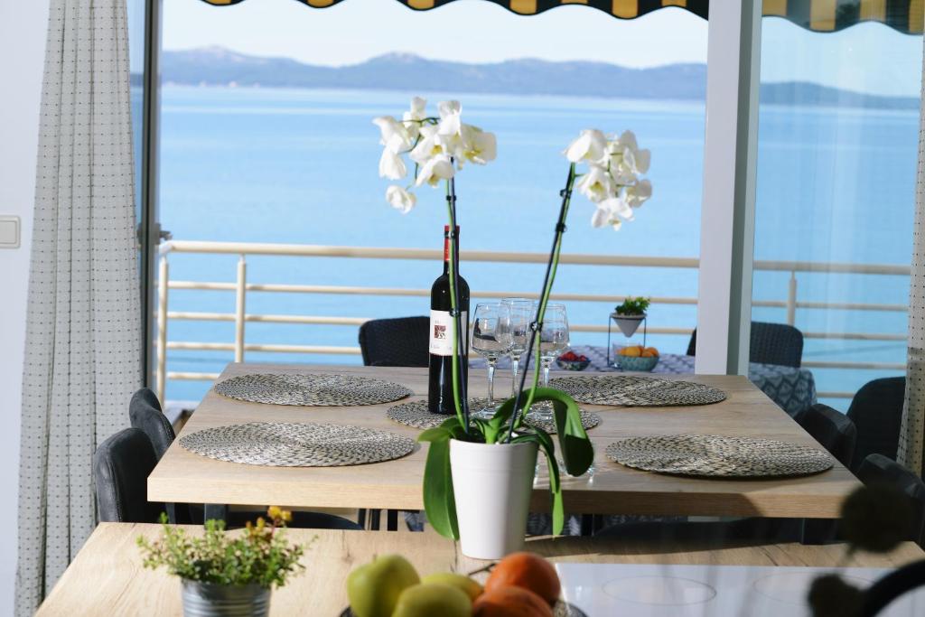 a table with a bottle of wine and flowers on it at Apartments Basioli in Zadar