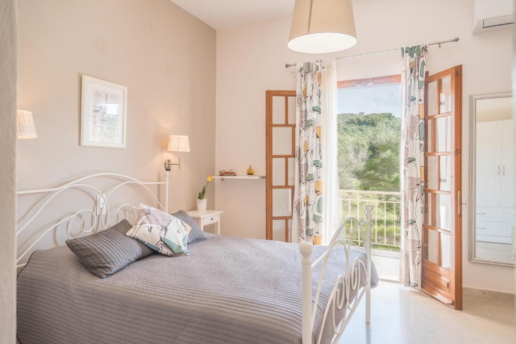 a white bedroom with a bed and a window at Nikos & Vivi Studios in Perivolion