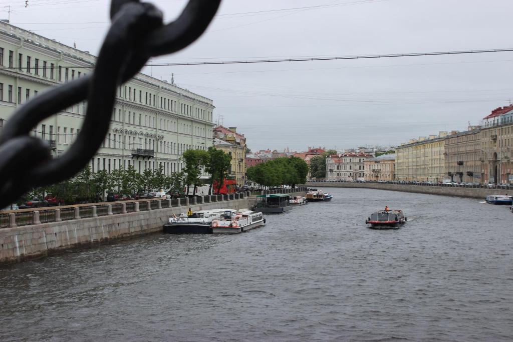 a group of boats in a river with buildings at Rinaldi Art in Saint Petersburg