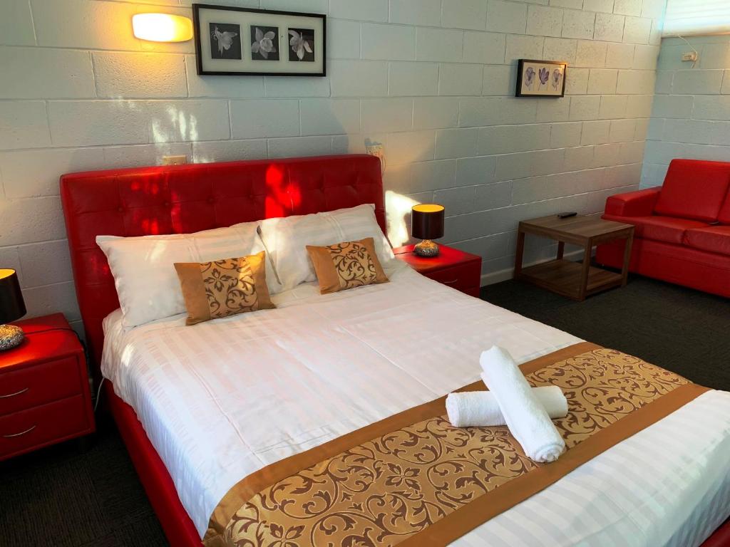 a bedroom with a large bed and a red couch at Gazebo Motor Inn in Strathmerton