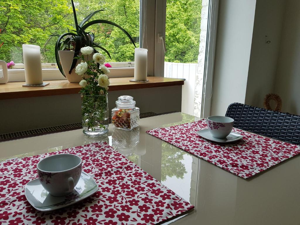 a table with two cups and a vase with candles at Scandinavian Breeze Apartment in Klaipėda