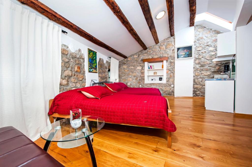 1 dormitorio con cama roja y mesa de cristal en Studios Villa Oscar, en Rovinj