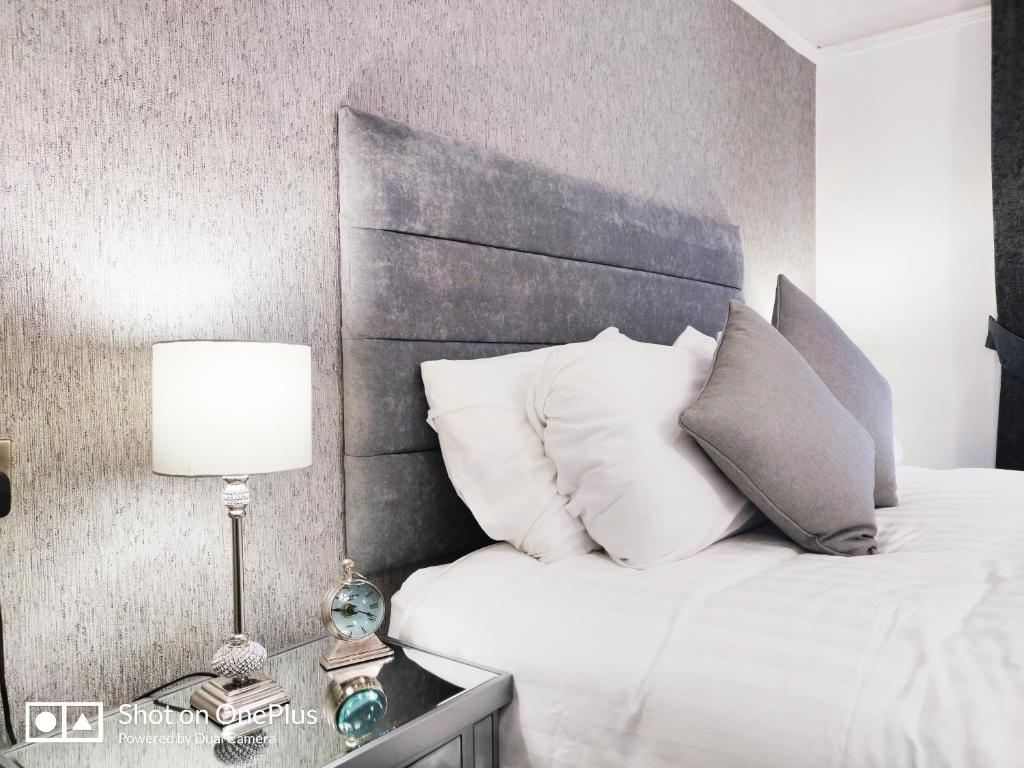 una camera da letto con un letto con cuscini bianchi e una lampada di Serendipity House a Londonderry