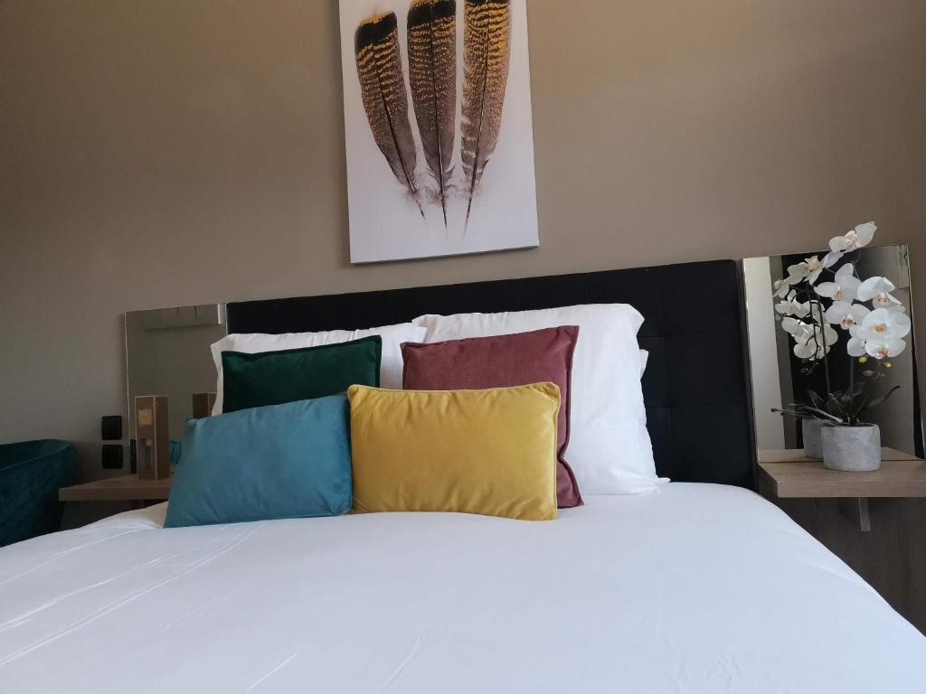 1 dormitorio con cama blanca y almohadas coloridas en Home Place Apartments - Langon Sauternes en Langon