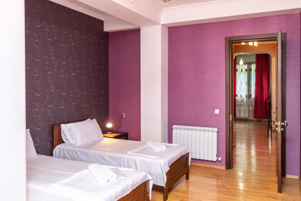 - 2 lits dans une chambre aux murs violets dans l'établissement Gnn Cosy Apartment, à Tbilissi