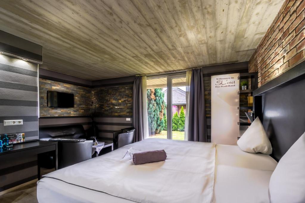 Un dormitorio con una gran cama blanca y una ventana en SL'otel - Das Stadthotel en Bernburg