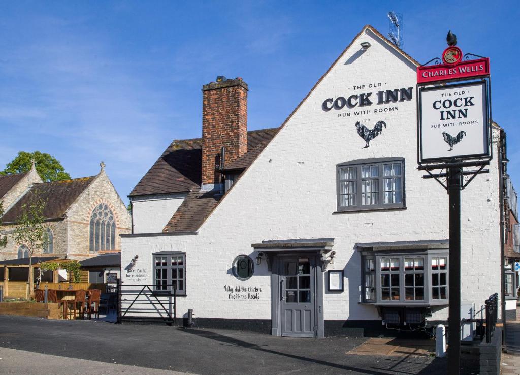 a white building with a crock inn on a street at The Old Cock Inn in Harpenden
