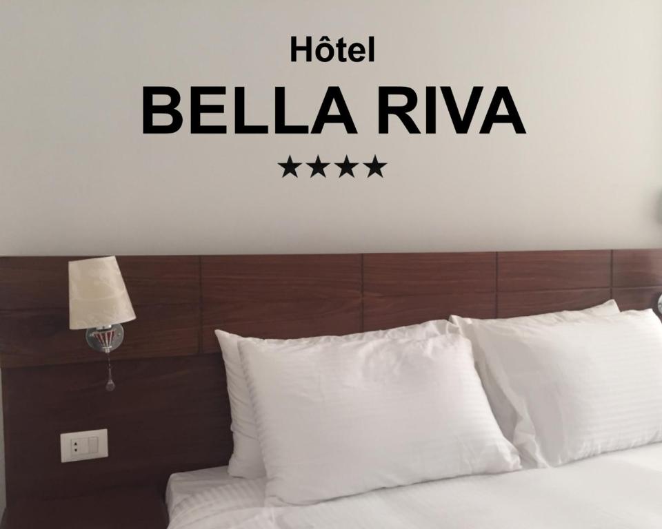 ein Schlafzimmer mit einem Bett mit einem Schild an der Wand des Hotels belka riya in der Unterkunft Hotel Bella Riva Kinshasa in Kinshasa